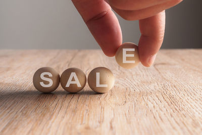 Cropped hand arranging balls with sale text on wooden table