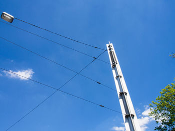 Low angle view of electricity pylon against blue sky