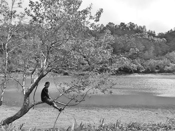 Man sitting by tree in lake