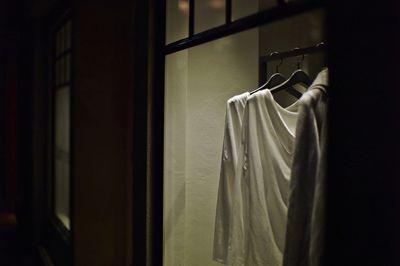 Clothes hanging on coathangers seen through glass window of store