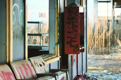 Weathered seats by pay phone at abandoned building