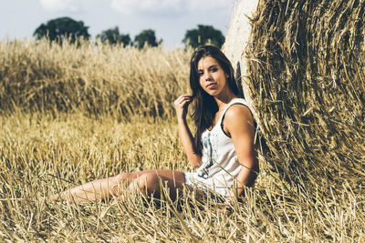 Portrait of smiling young woman sitting on field