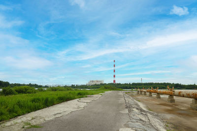 Road by factory against sky