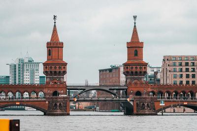 Arch bridge over river against buildings in city