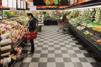 People buying vegetables while standing in supermarket