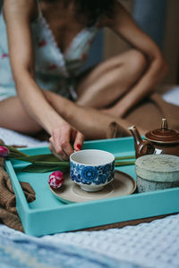 Midsection of sensuous woman holding drink sitting on table