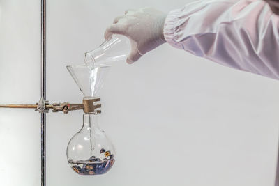 Cropped hand of scientist experimenting against white background