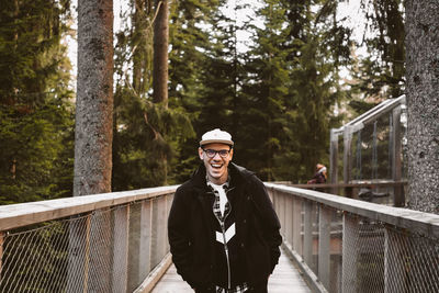 Portrait of smiling man standing on footbridge