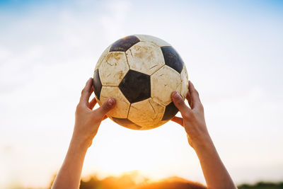 Low angle view of hand playing soccer ball against sky