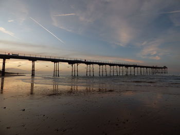 Bridge over sea against sky at sunset