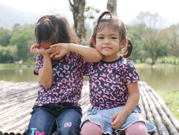 Portrait of cute girl sitting with sister outdoors