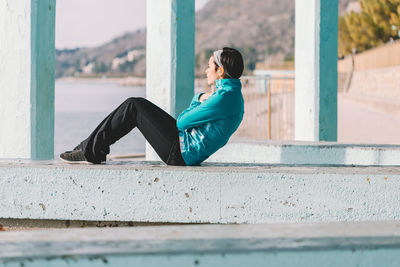 Side view of man sitting on wall