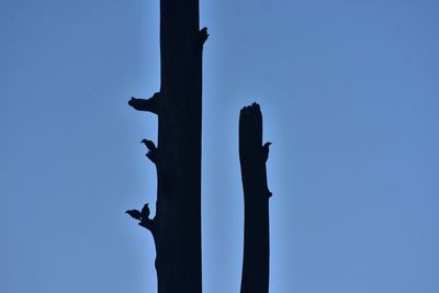 Low angle view of silhouette statue against clear blue sky