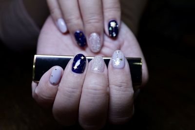 Close-up of nail art on woman hands against black background