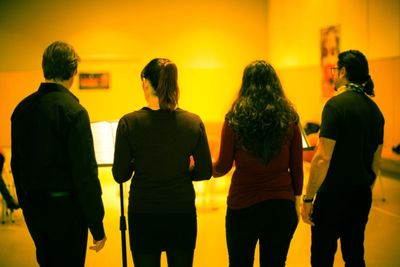 Rear view of people standing against the wall