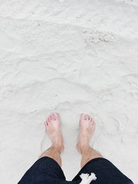 Low section of man standing on sand