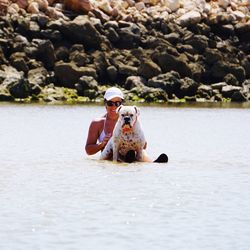 Woman sitting in lake with dog