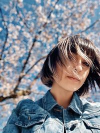 Low angle portrait of young woman with tousled hair in park during spring