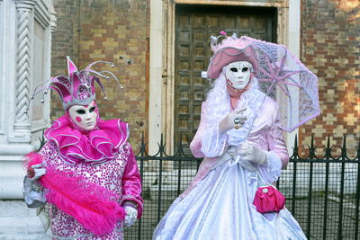 People wearing venetian mask and costume while standing outdoors