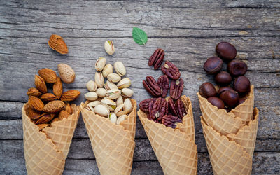 High angle view of ice cream cones with nuts on wooden table