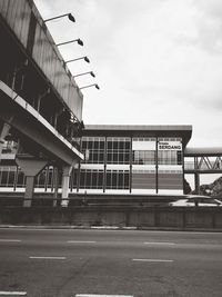 Low angle view of bridge by buildings against sky