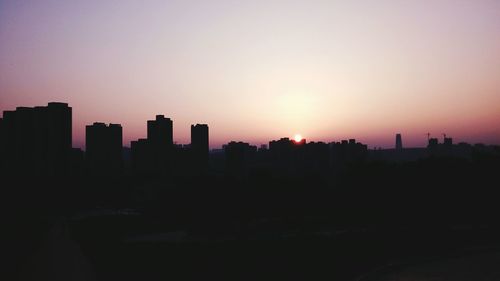 Silhouette buildings against clear sky at sunset