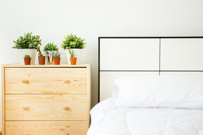 Potted plants on nightstand by bed at home