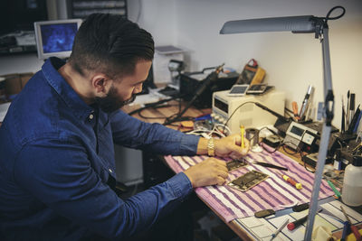 Male engineer repairing mobile phone at table in workshop