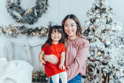 Portrait of young woman standing by christmas tree