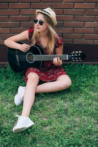 Young woman wearing sunglasses sitting on grass