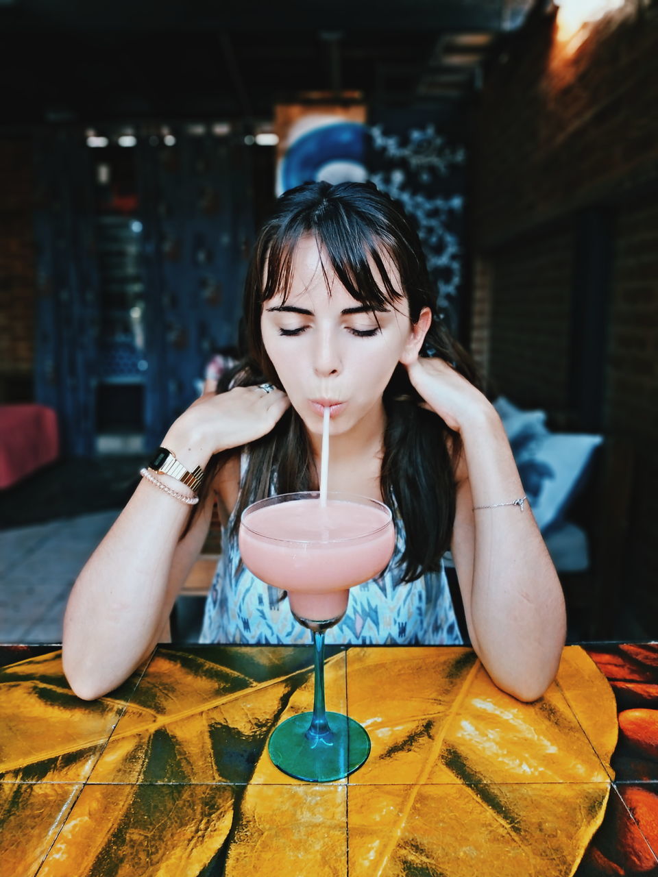 one person, real people, front view, lifestyles, indoors, sitting, hairstyle, hair, table, portrait, women, long hair, leisure activity, food and drink, focus on foreground, restaurant, young adult, girls, bangs, contemplation