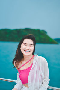 Portrait of young woman standing against lake