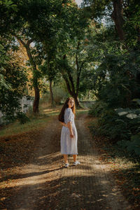 Full length of woman walking on road in forest