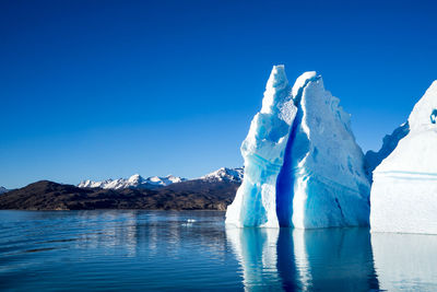 Scenic view of lake against mountain during winter against blue sky