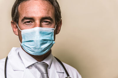 Close-up portrait of doctor wearing mask against colored background