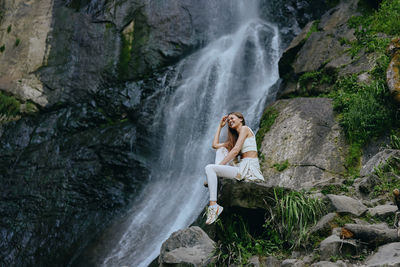 Rear view of woman standing against waterfall