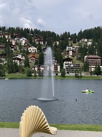 Fountain in lake against buildings in city