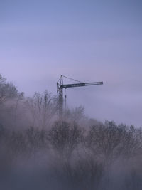 Low angle view of silhouette crane against sky at dusk