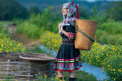 Woman holding umbrella while standing by wicker basket