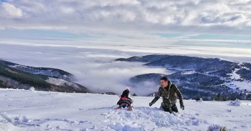 People on snow covered land against sky