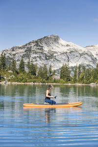 Man in boat on lake against mountain range