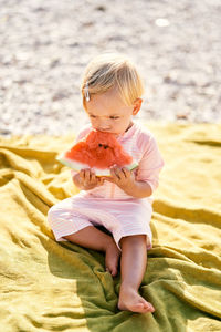 Side view of cute girl sitting on beach