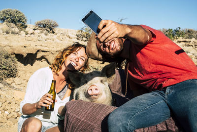 Man taking selfie with woman and pig 
