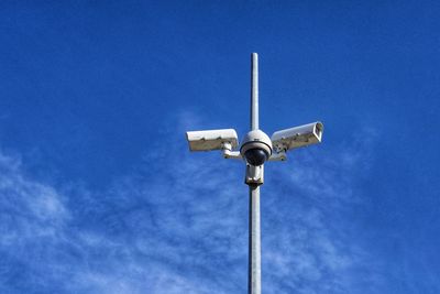 Low angle view of security cameras against blue sky