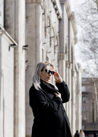 Young woman standing against built structure