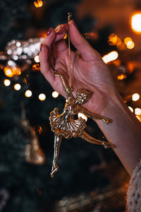 Cropped hand of woman holding illuminated string lights at night