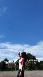 Women standing by tree against sky