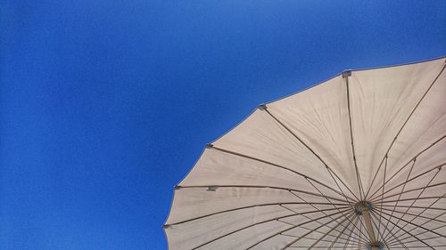 Low angle view of umbrella against clear blue sky