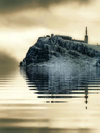 Reflection of building on sea against sky