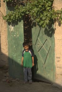 Full length portrait of boy standing by tree